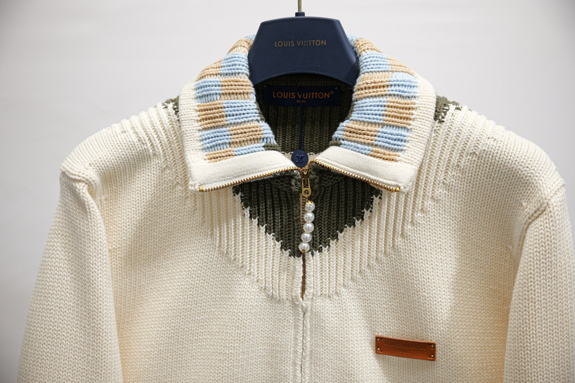 Ivory knit zip-up jacket with striped collar, pearl placket, and gold zipper
