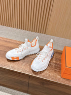 Hermes unisex sneakers, side view in white with orange inner pull tabs.