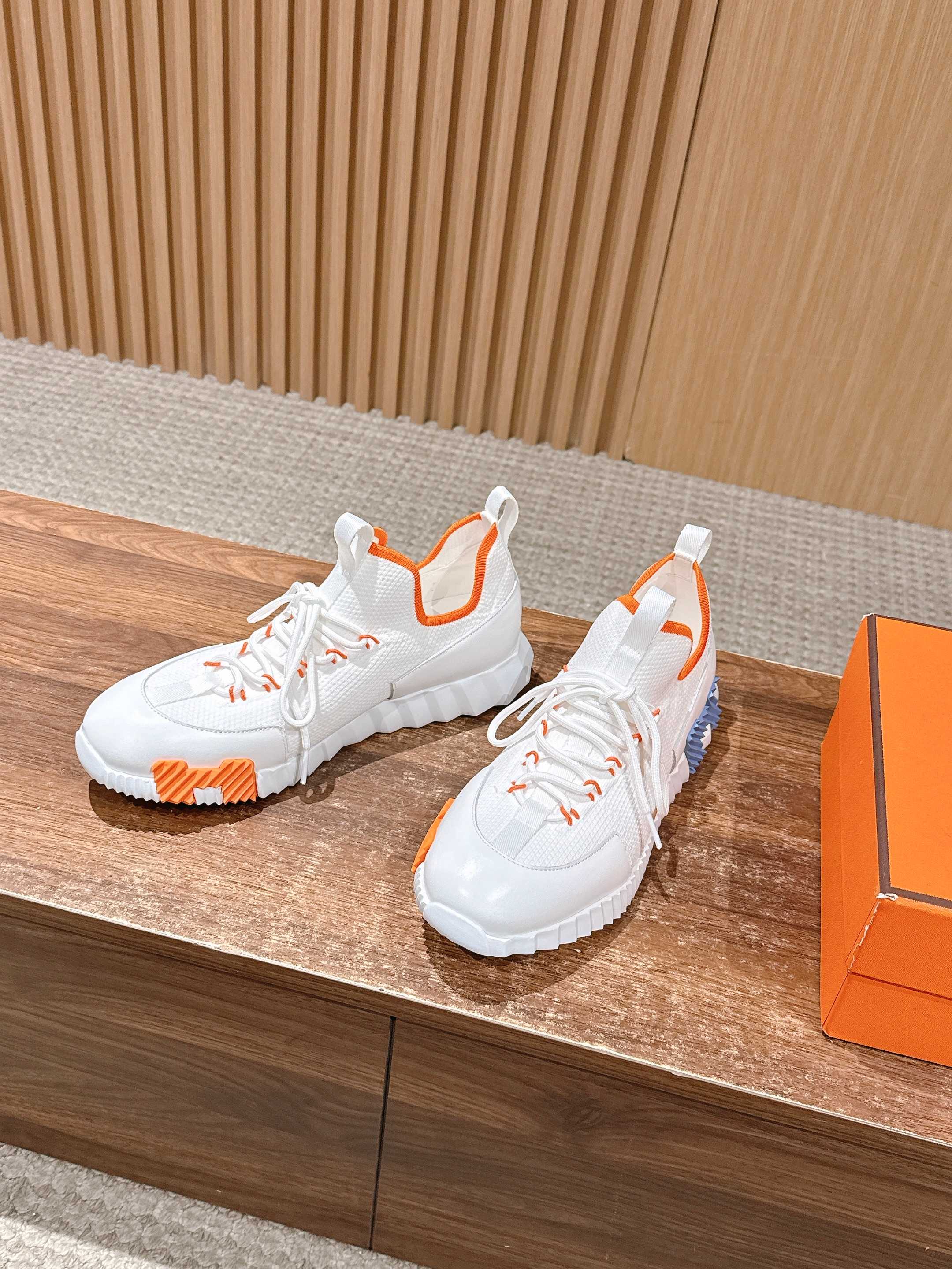 Hermes unisex sneakers, side view in white with orange inner pull tabs.