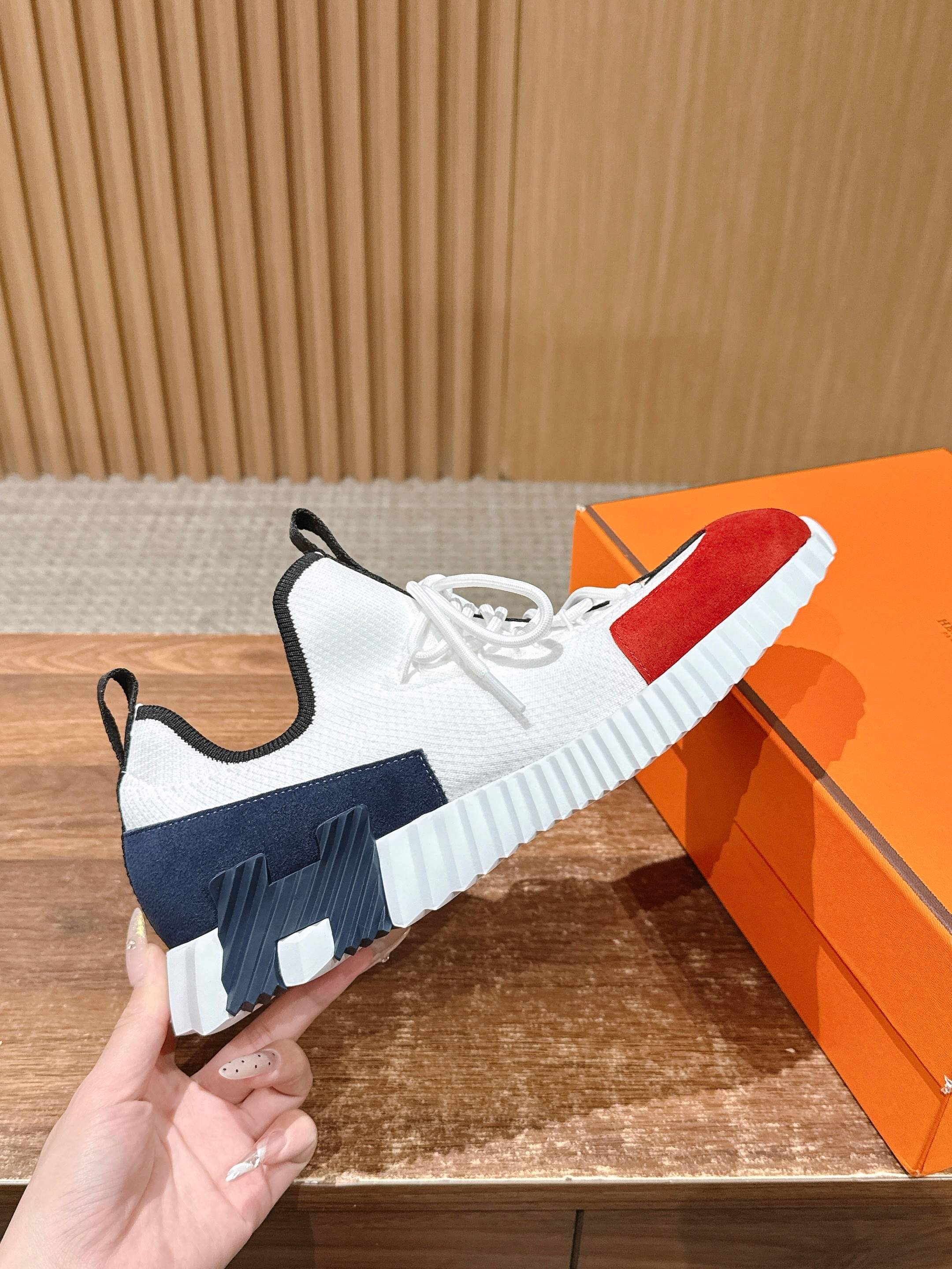 Unisex sneaker detail: white upper with red and navy sections, thick sole, lace-up