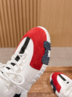 Close-up of unisex sneaker heel and side: red suede panel, navy sole tread, white laces