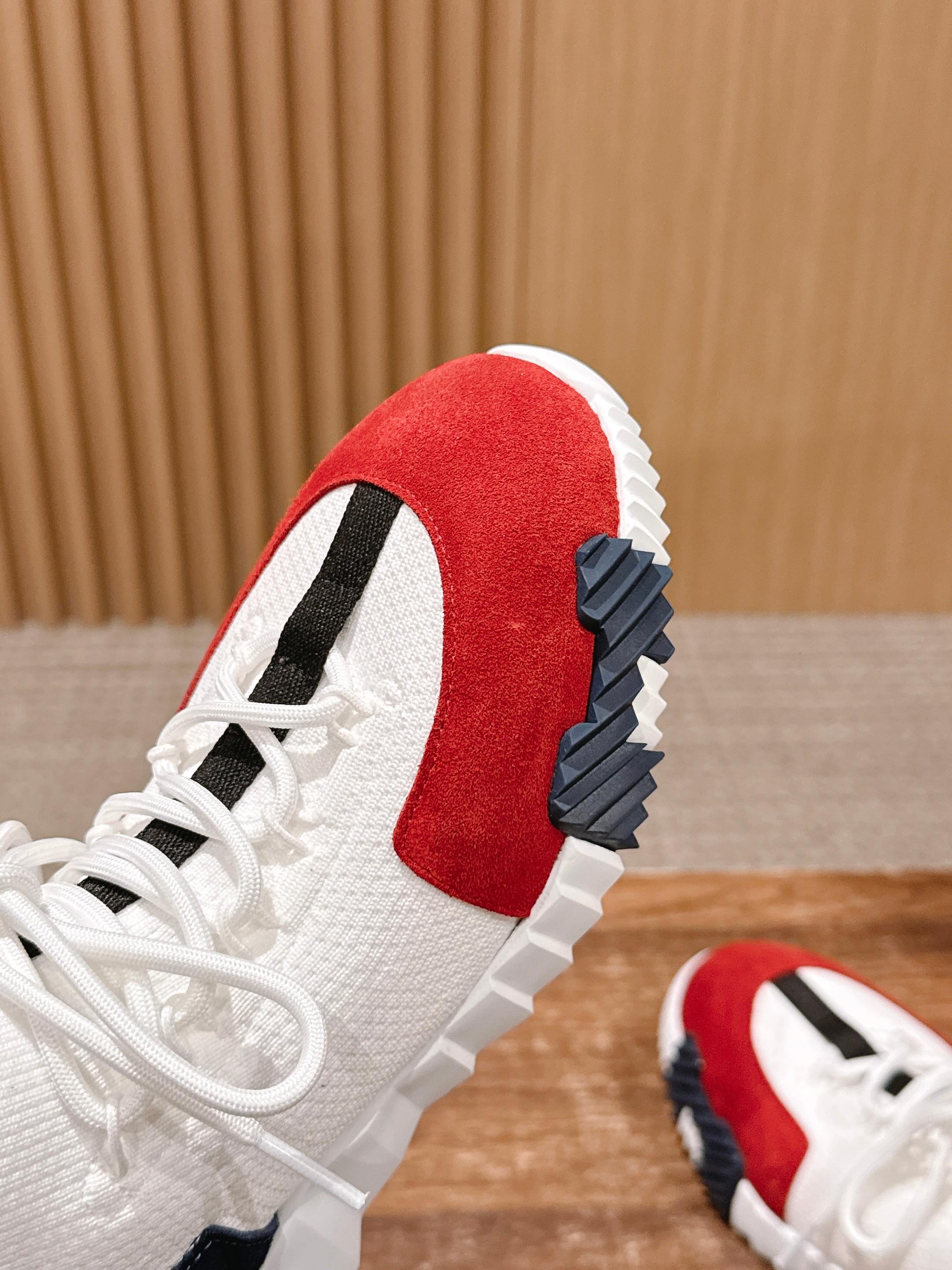 Close-up of unisex sneaker heel and side: red suede panel, navy sole tread, white laces