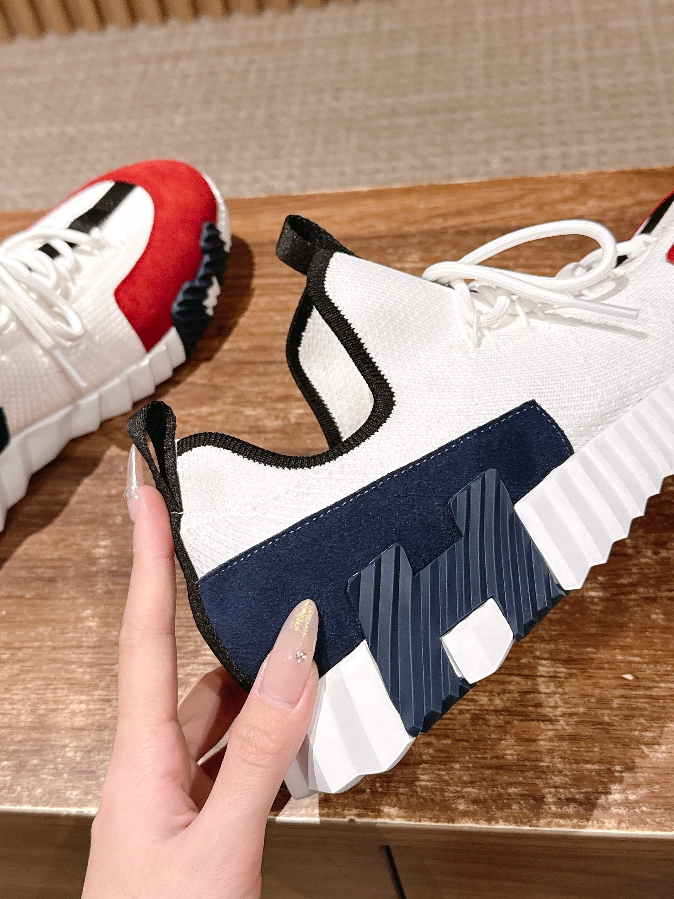 Unisex sneaker side view: navy and red panels, black trim, white laces, textured sole