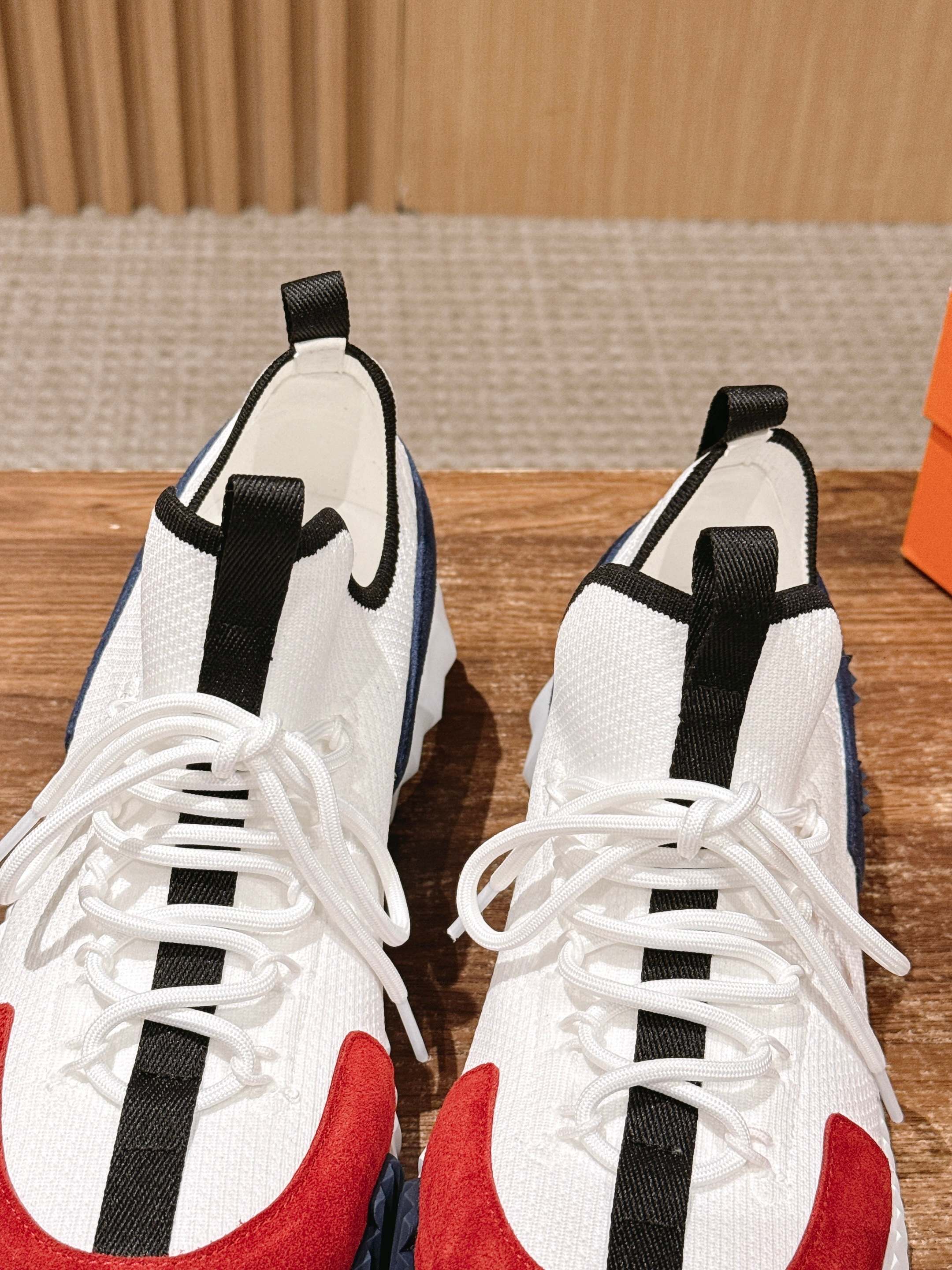 Unisex sneakers front view: white upper, black straps, red toe accent, lace closure