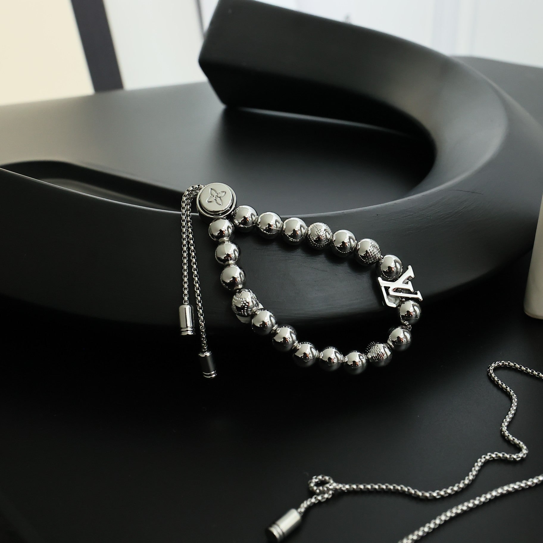 Louis Vuitton beaded bracelet with round silver beads, chain tassel, and LV charm