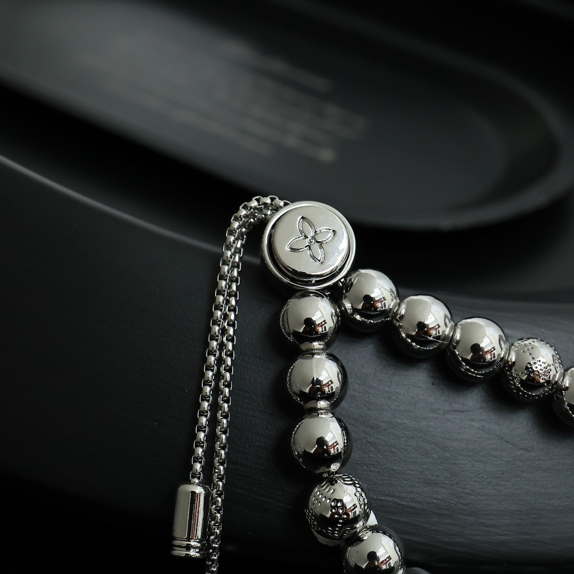 Louis Vuitton beaded bracelet with round silver beads and small flower emblem medallion