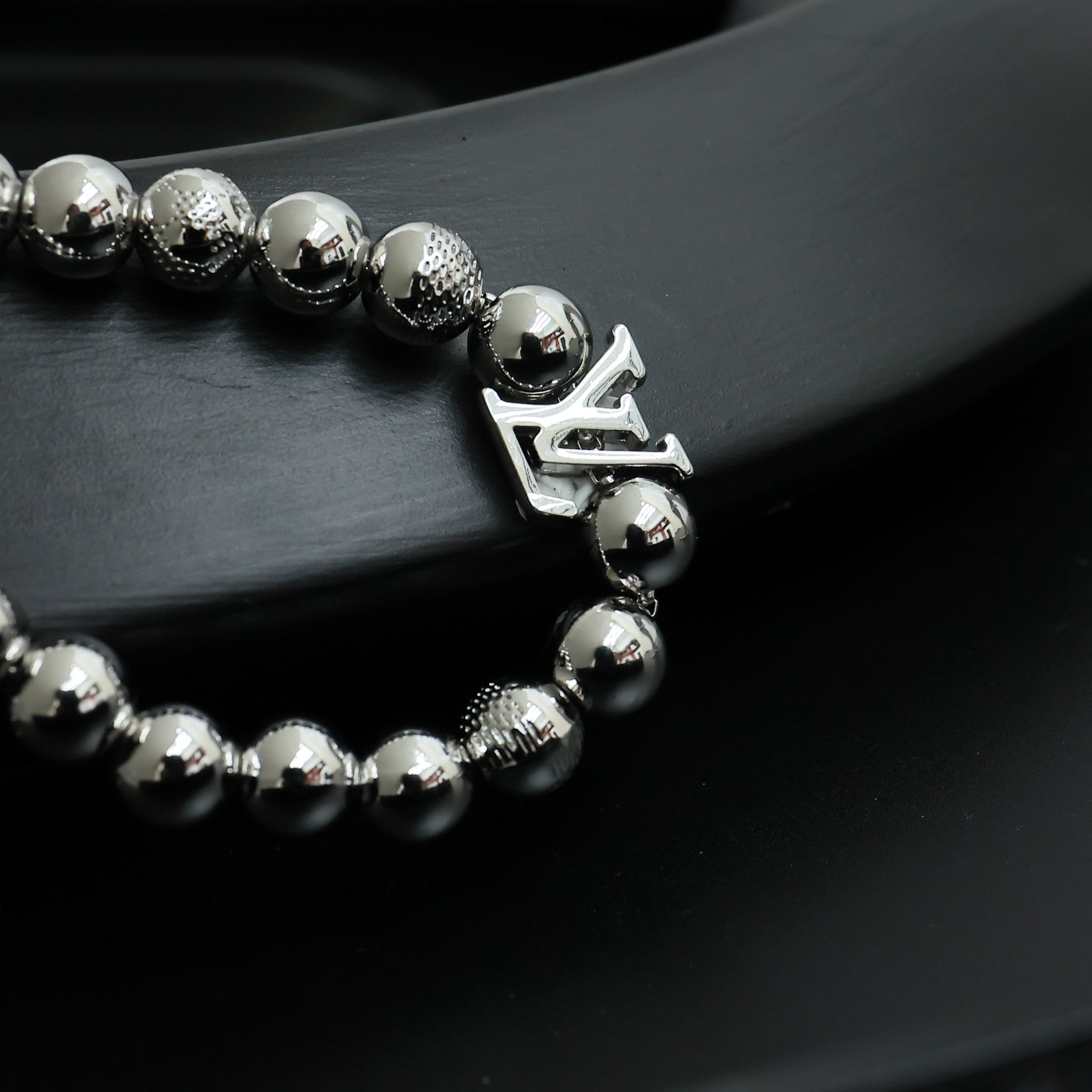 Louis Vuitton beaded bracelet with round silver beads and dangling LV logo charm