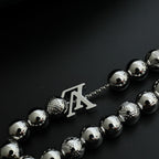 Beaded necklace section with silver-toned beads and LV-style letter charm