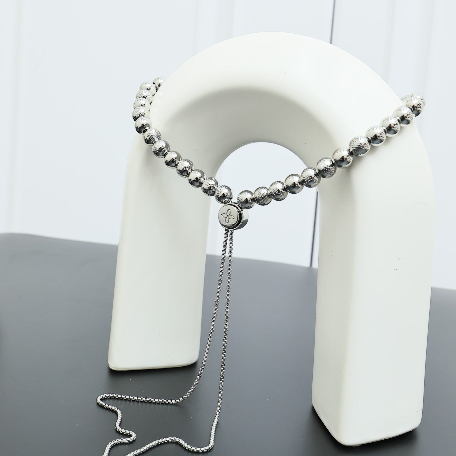 Beaded necklace draped on a white display stand with silver-toned bead chain