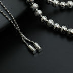 Beaded necklace close-up with silver-toned chain ends and small cylindrical tips
