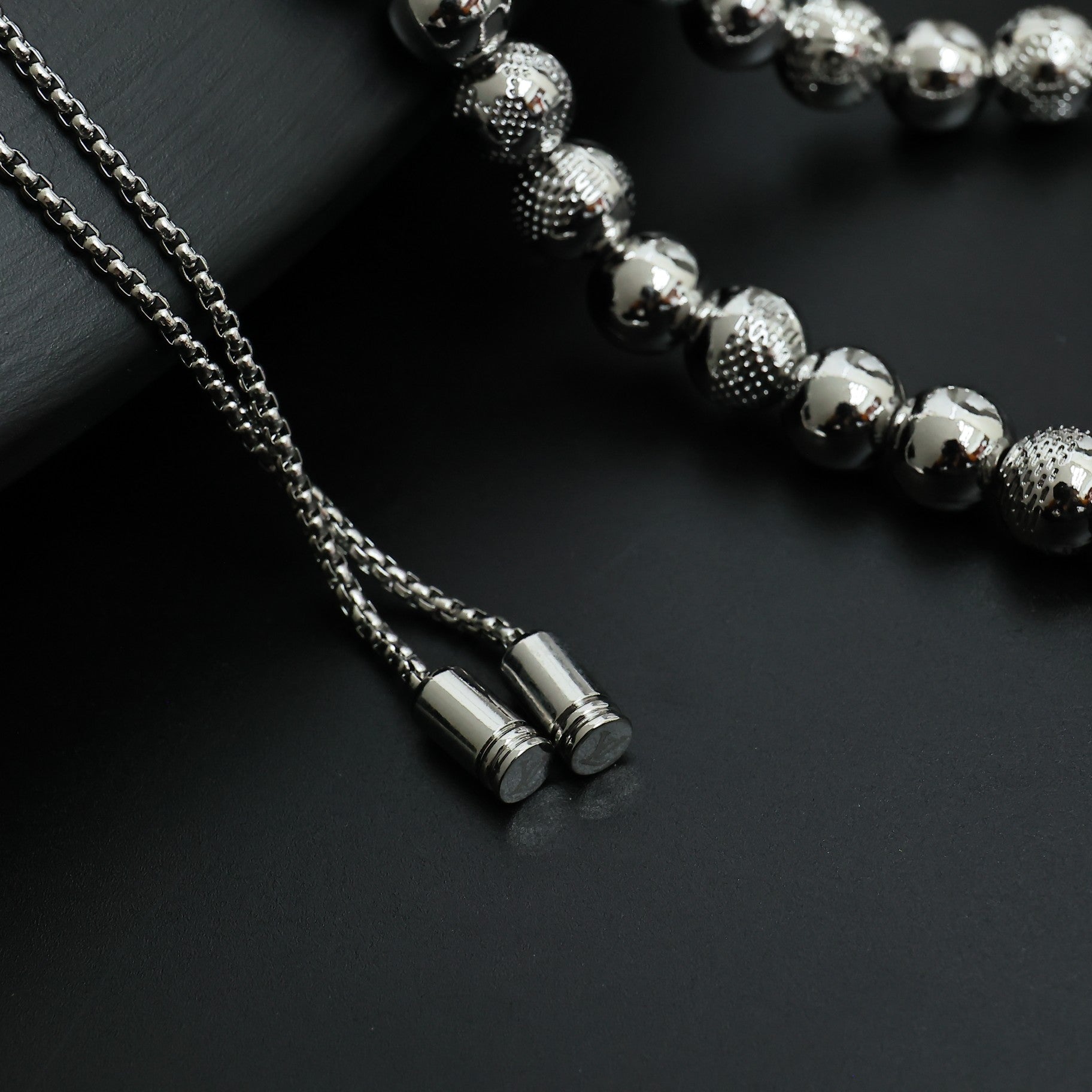 Beaded necklace close-up with silver-toned chain ends and small cylindrical tips