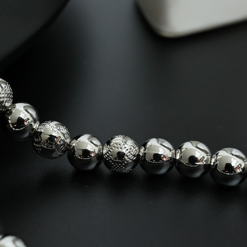Beaded necklace close-up with silver-toned spherical beads in a single strand
