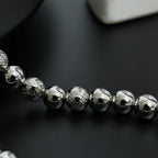 Beaded necklace close-up with silver-toned spherical beads in a single strand