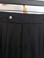 Black pants with button waist closure and neatly pressed front pleats