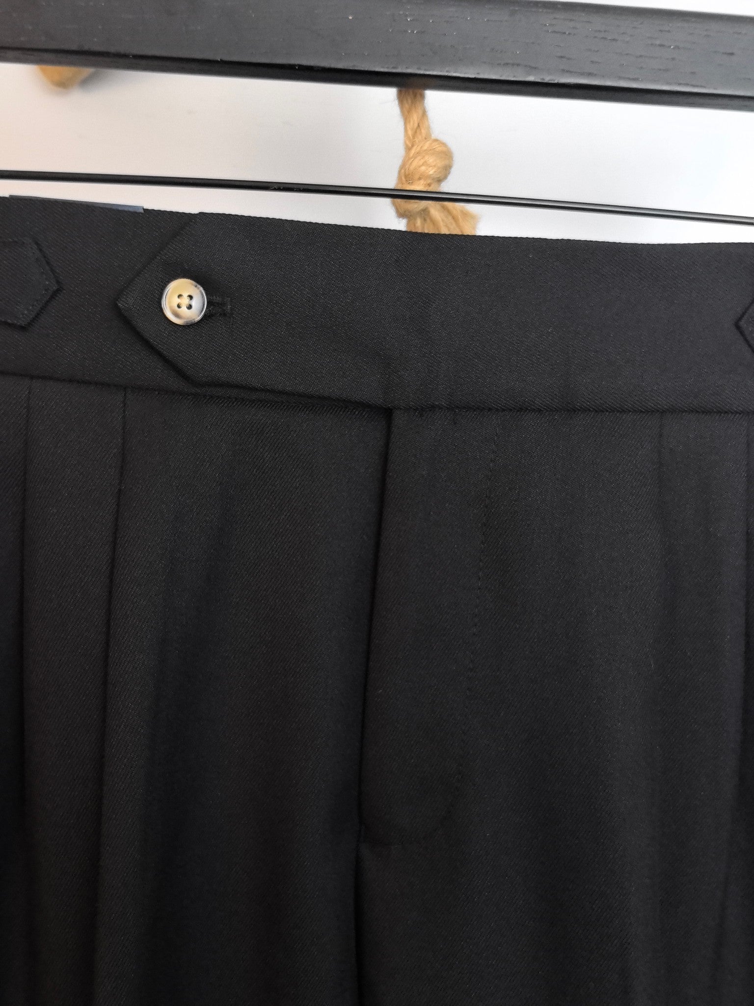 Black pants with button waist closure and neatly pressed front pleats