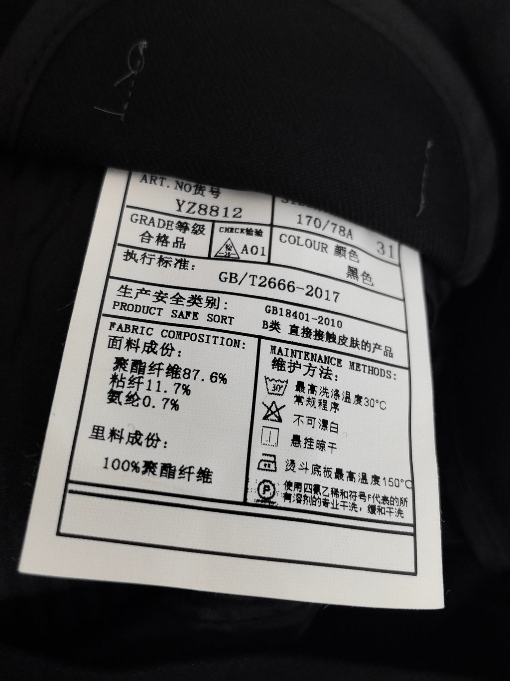 Internal fabric care label on black pants, with product and composition info