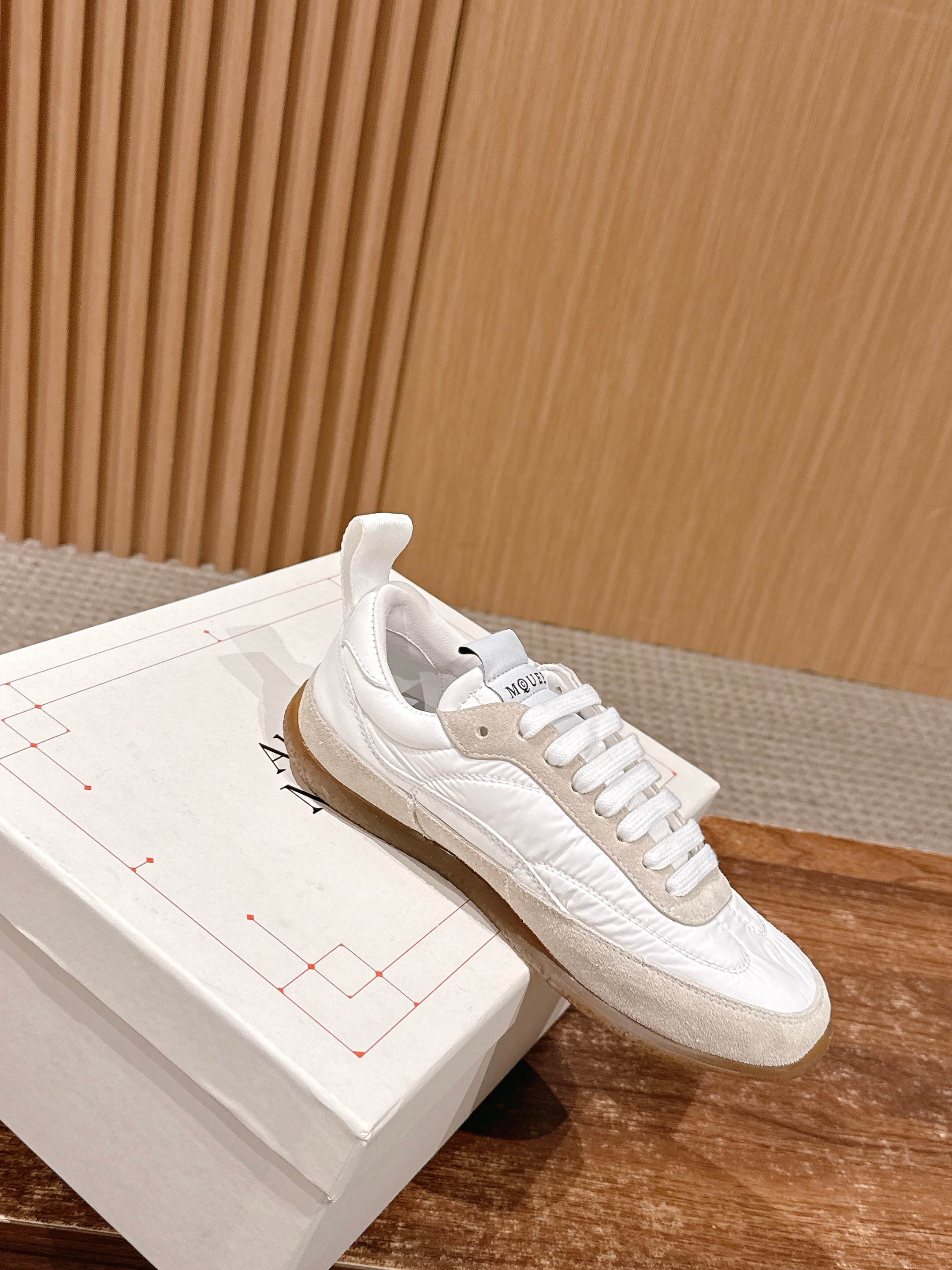 White lace-up sneakers on a box with logo on heel tab