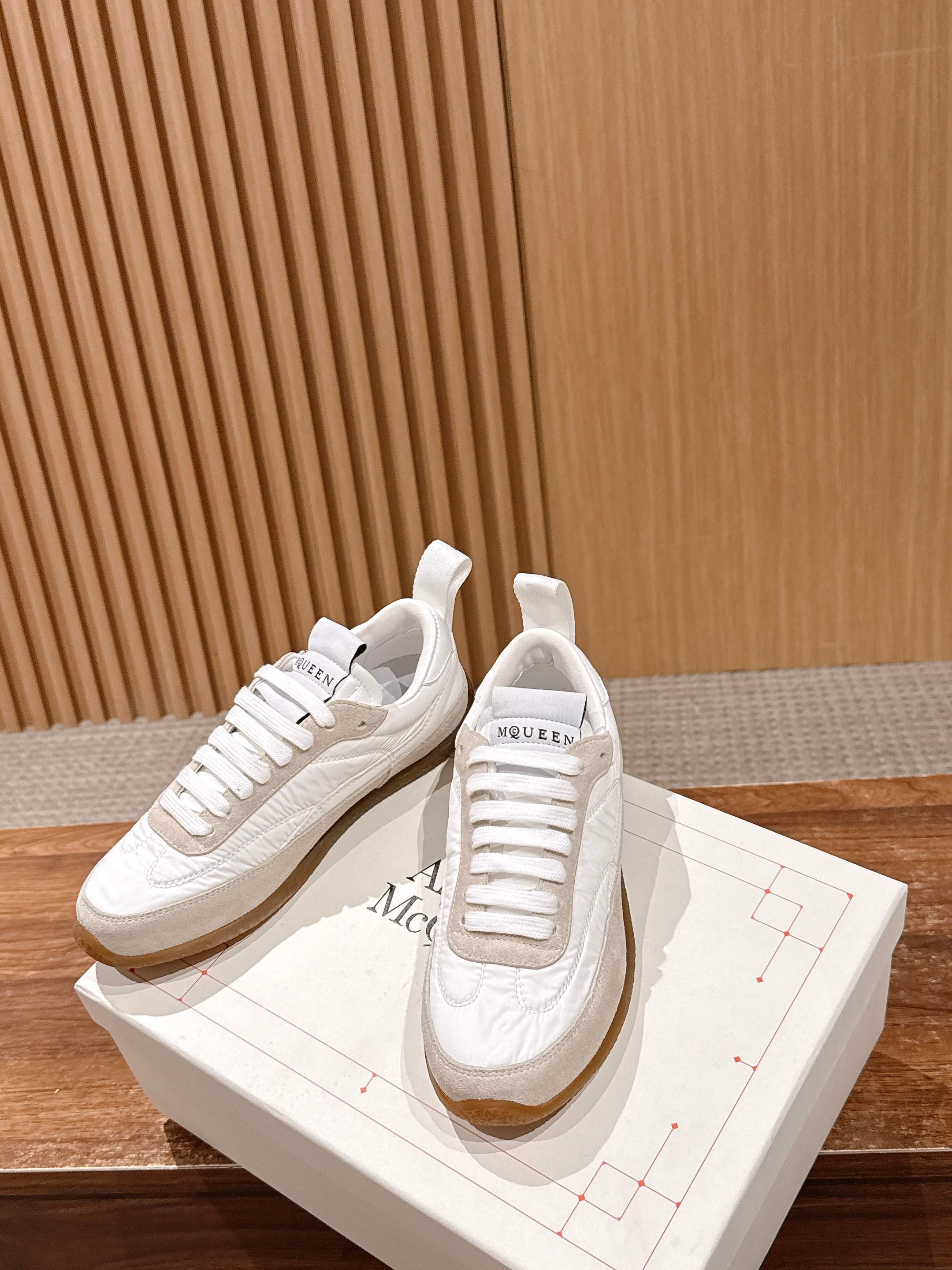 White lace-up sneakers with beige trim, resting on a white shoebox