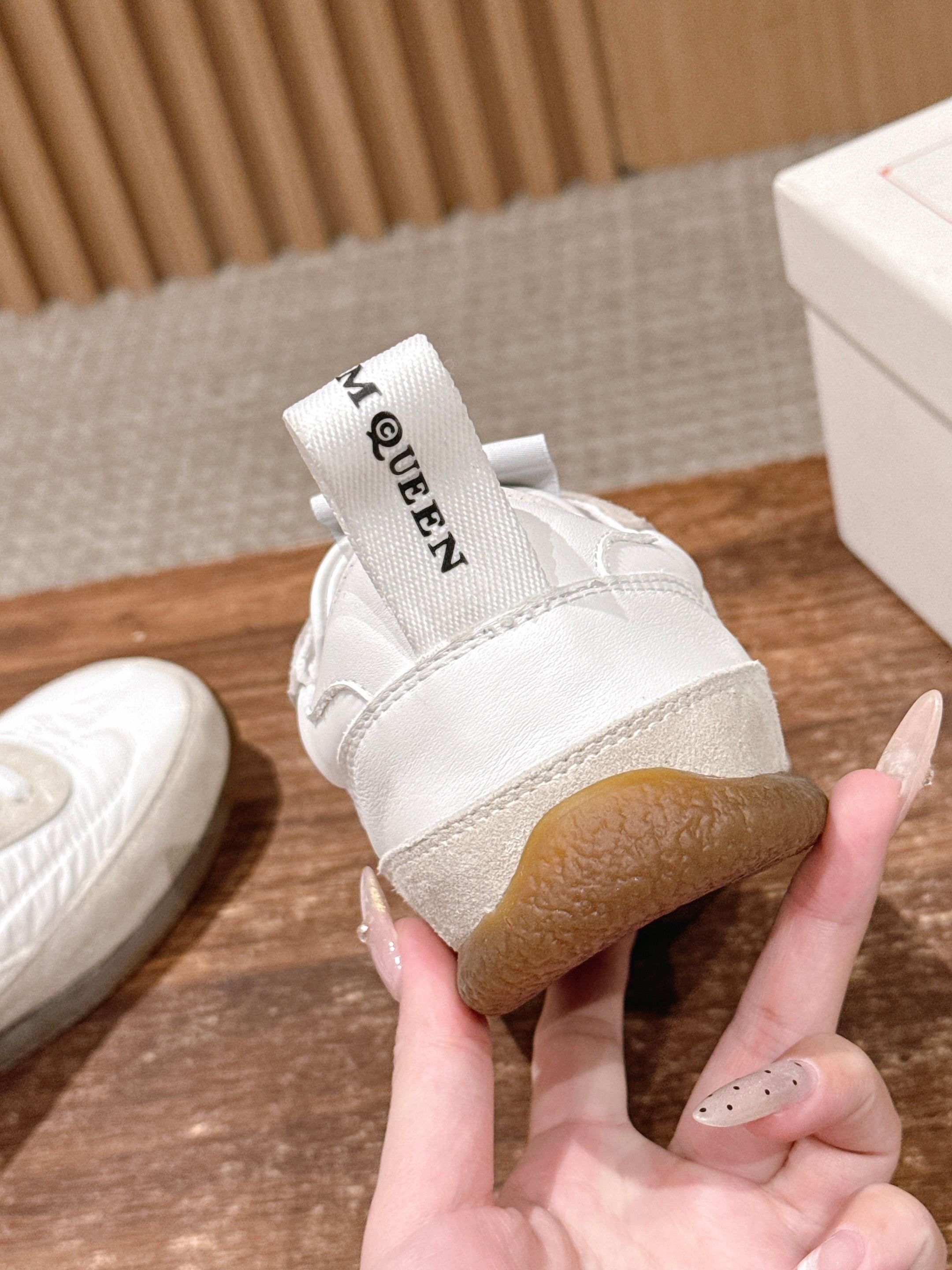 Back view of white sneakers with logo heel patch and beige rubber sole
