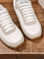 Close-up of white sneakers showing lace eyelets and beige side panels