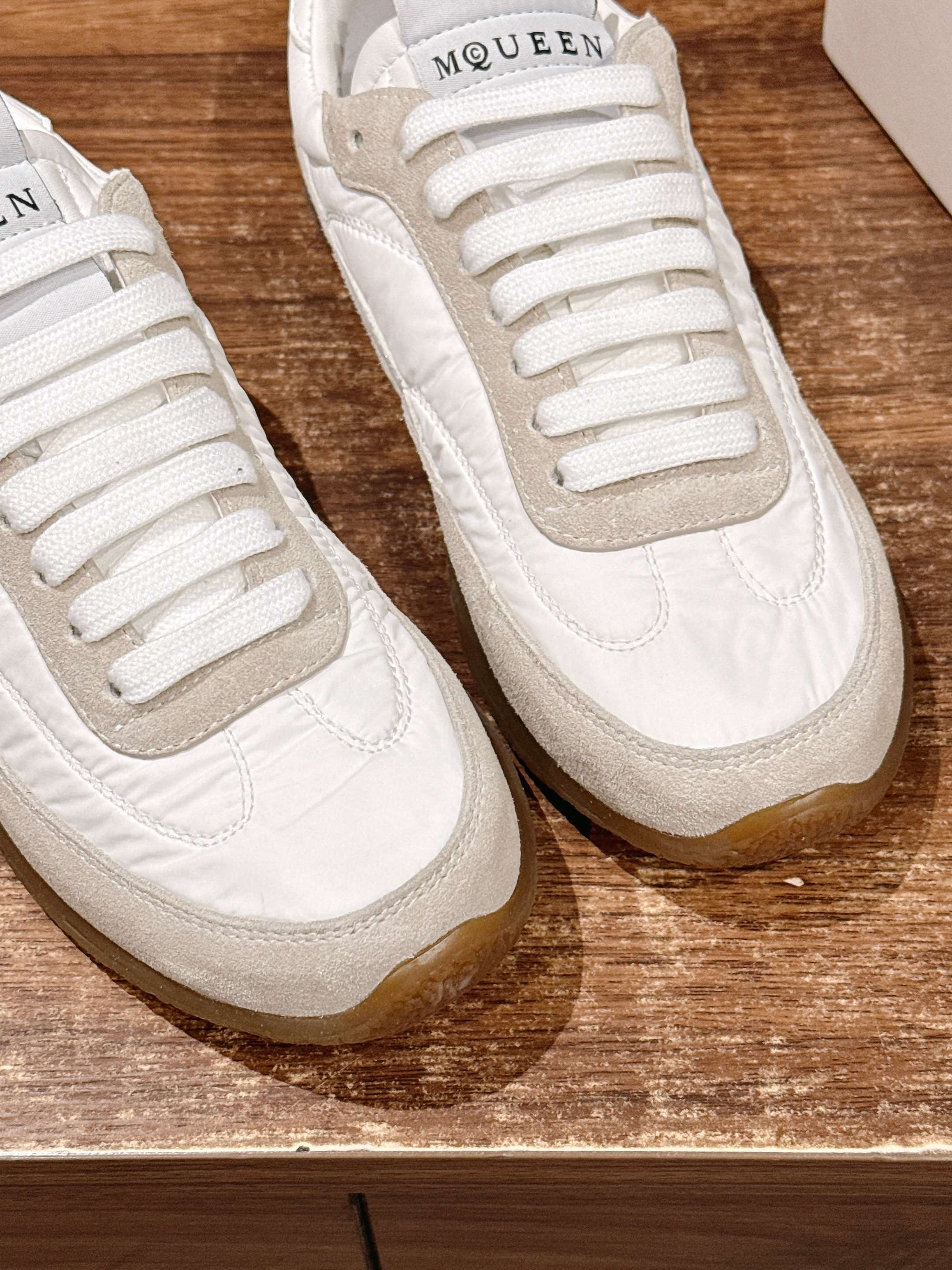 Close-up of white sneakers showing lace eyelets and beige side panels