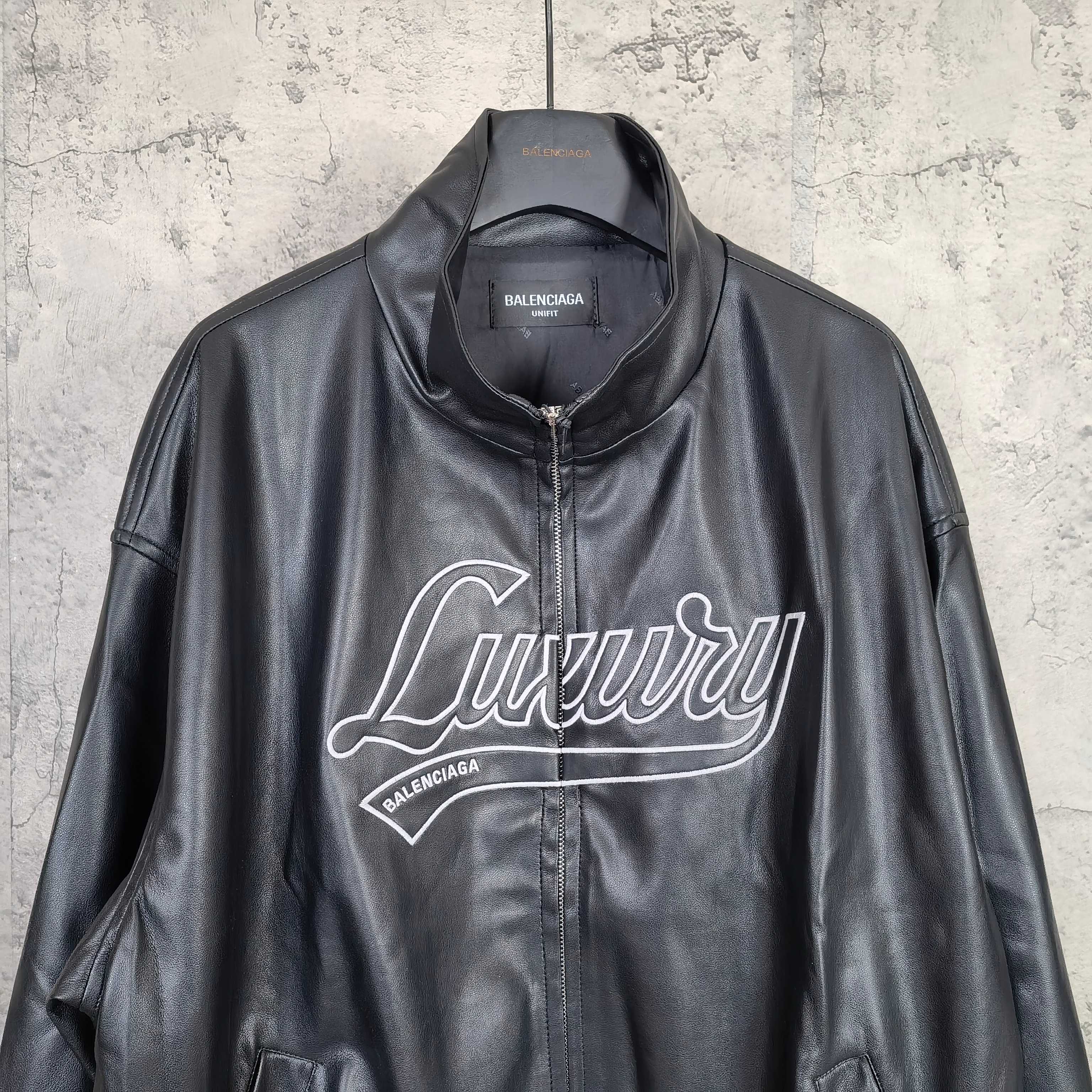 Black leather zip-up jacket with stand collar and white “Luxury” logo