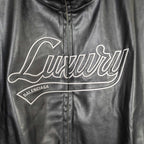 Black leather jacket front close-up of white “Luxury” logo and zip