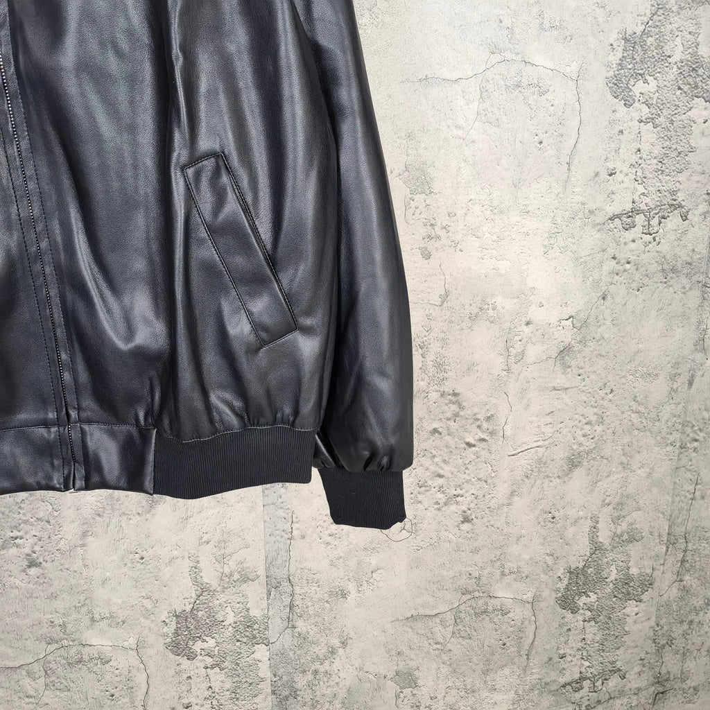 Dark leather jacket sleeve with side pocket and ribbed cuffs, partial front view