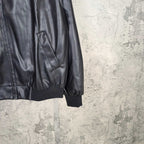 Dark leather jacket sleeve with side pocket and ribbed cuffs, partial front view