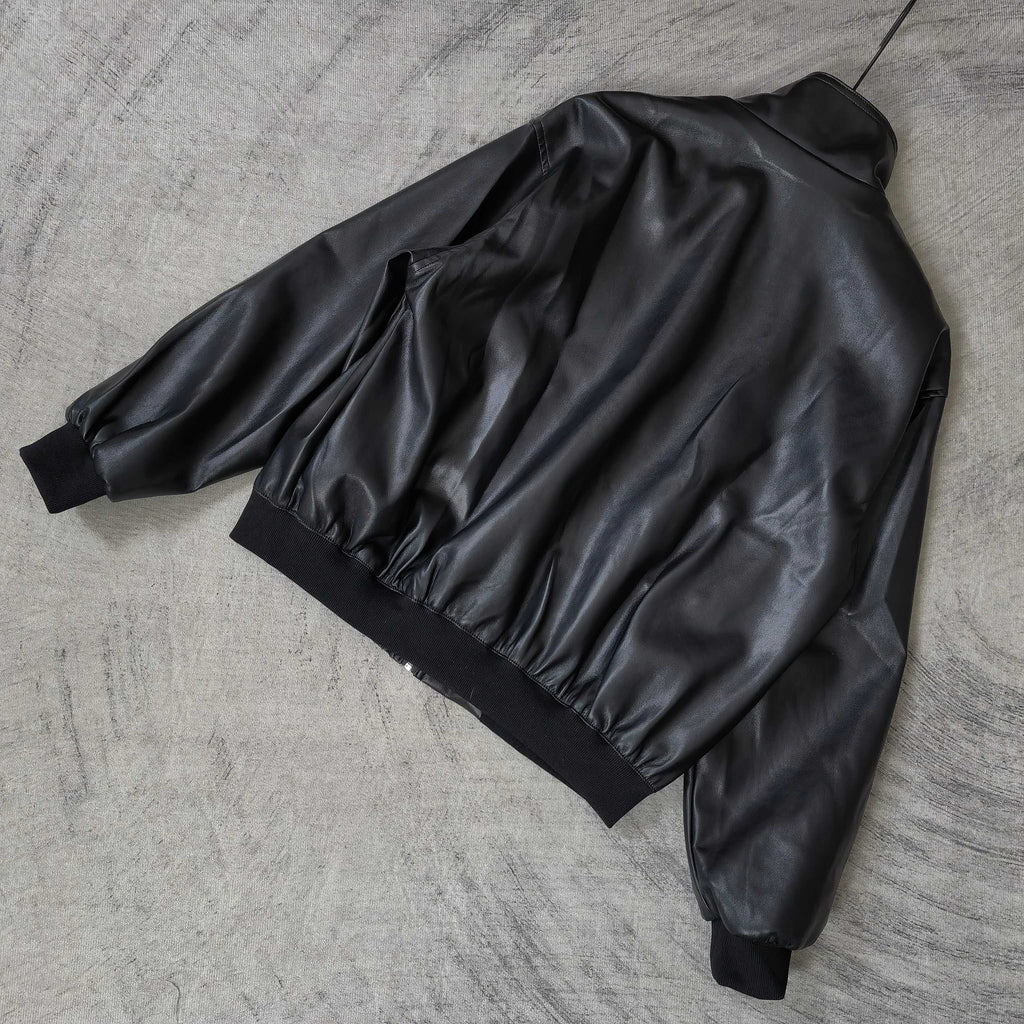 Balenciaga dark leather jacket laid flat, showing gathered back and ribbed cuffs