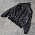 Balenciaga dark leather jacket laid flat, showing gathered back and ribbed cuffs