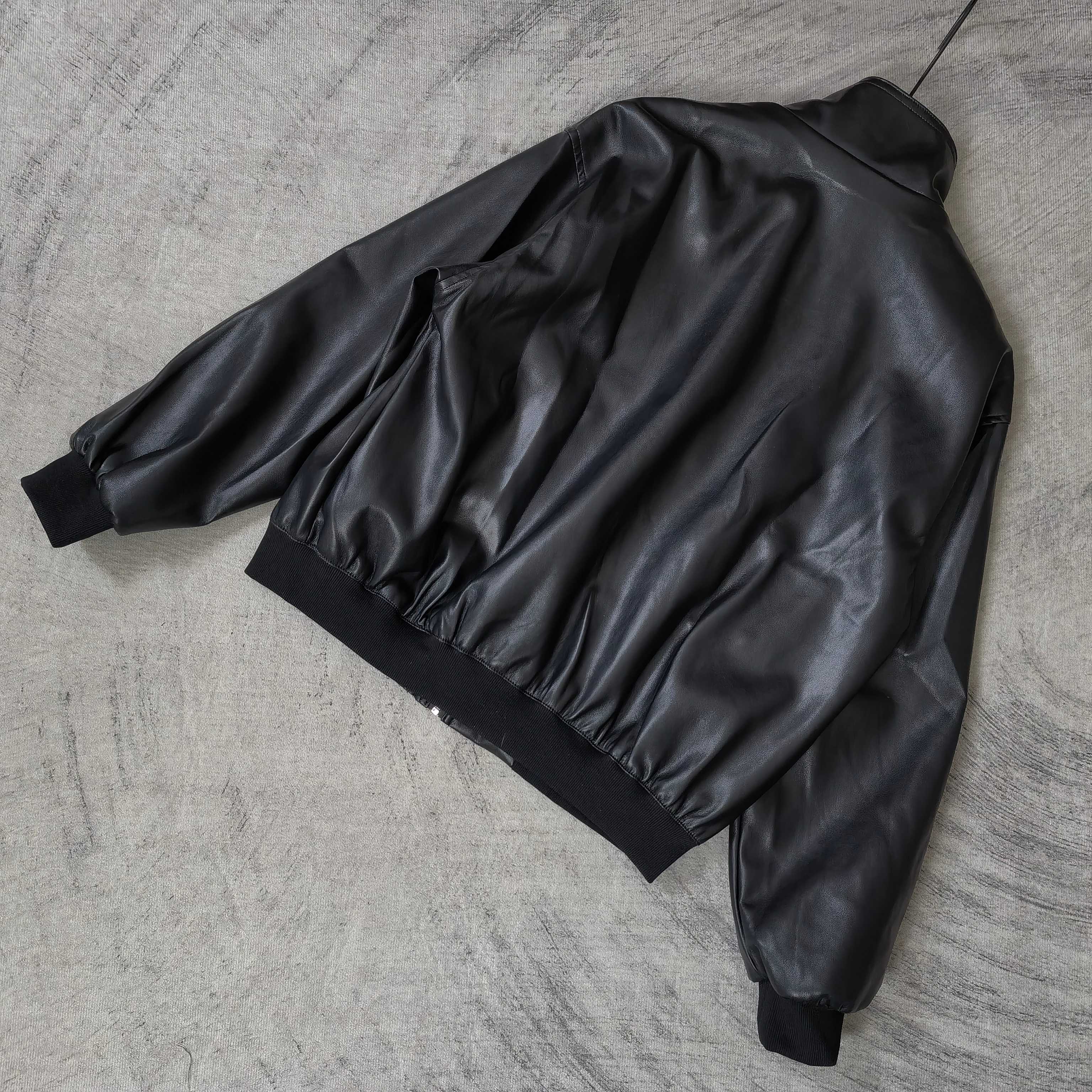 Balenciaga dark leather jacket laid flat, showing gathered back and ribbed cuffs