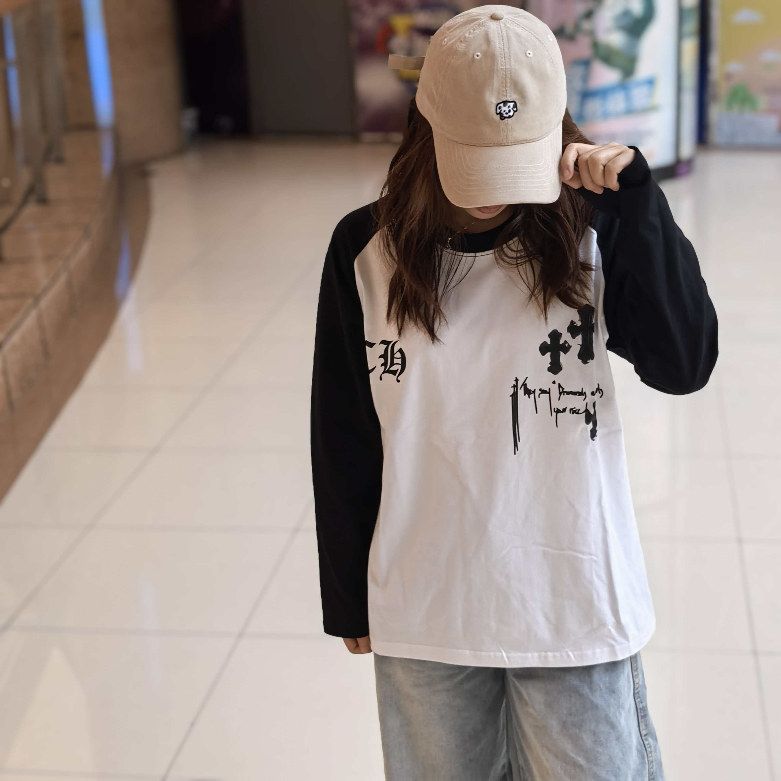 Long-sleeve raglan shirt with black sleeves, white body, and gothic chest graphic