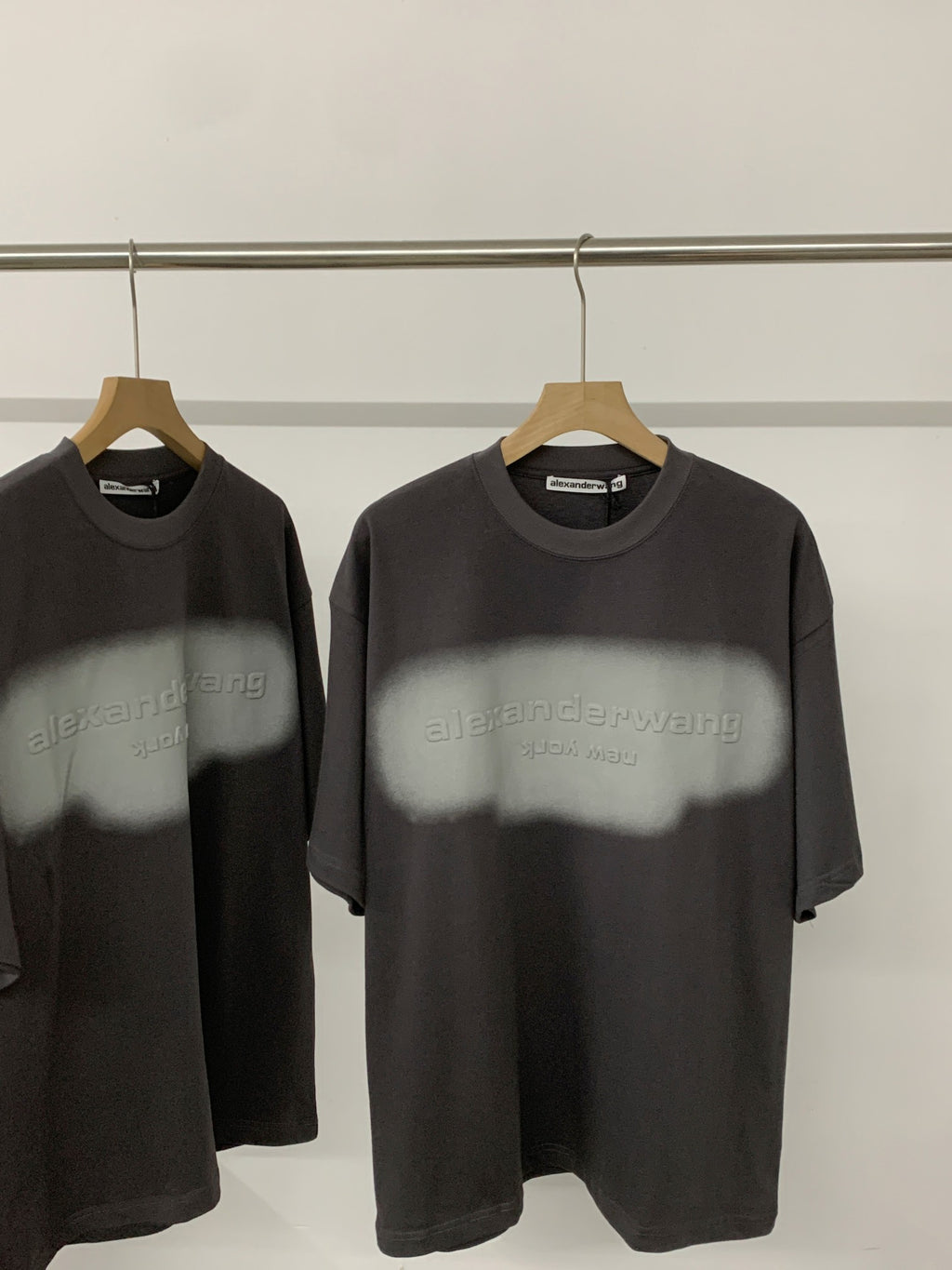 Black short-sleeve T-shirt with crew neck and faint logo graphic