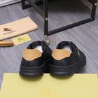 Black Burberry low-top sneakers with tan heel tabs and ridged rubber sole.