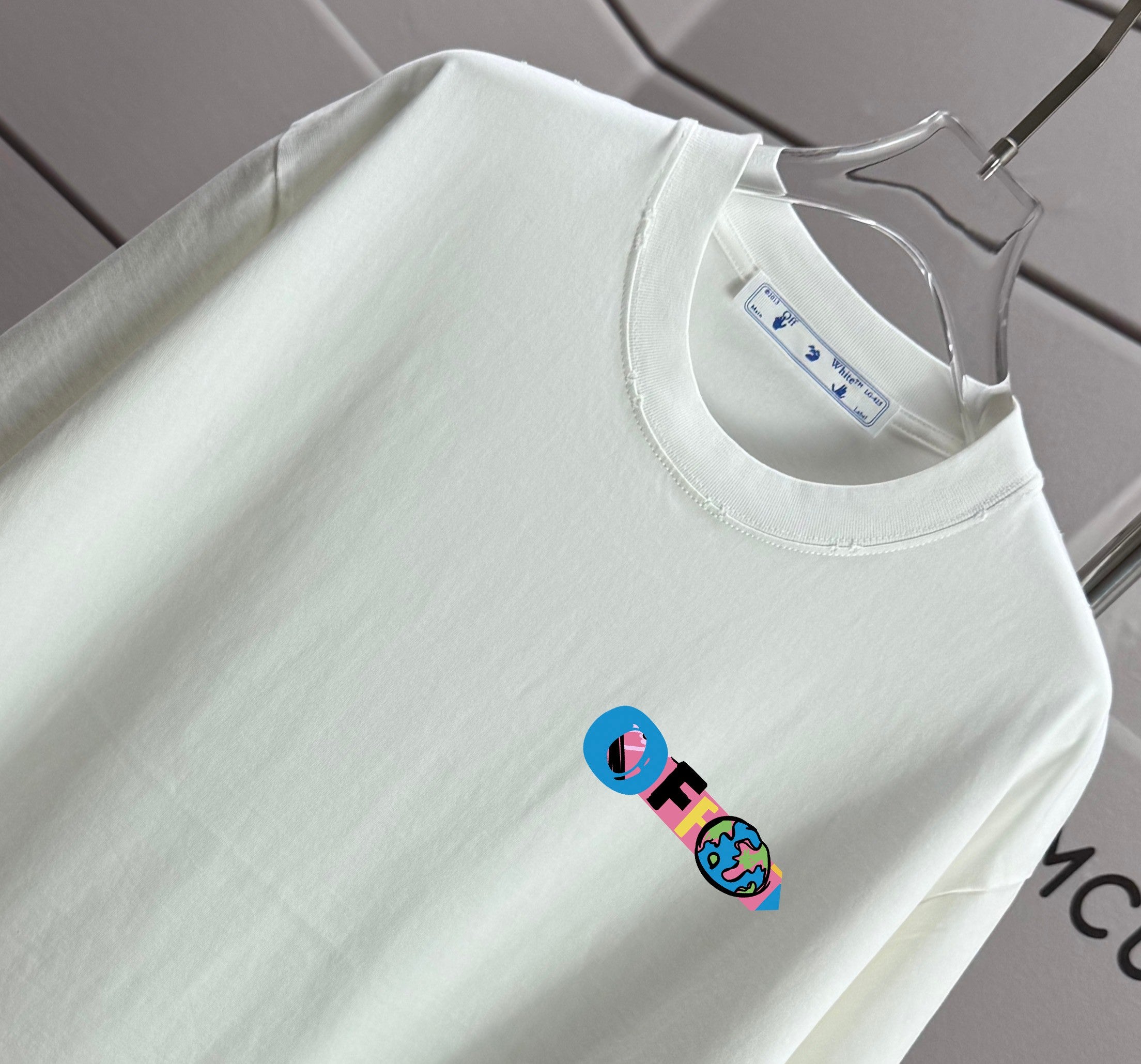 Off-white T-shirt showing crew neck and small chest logo graphic