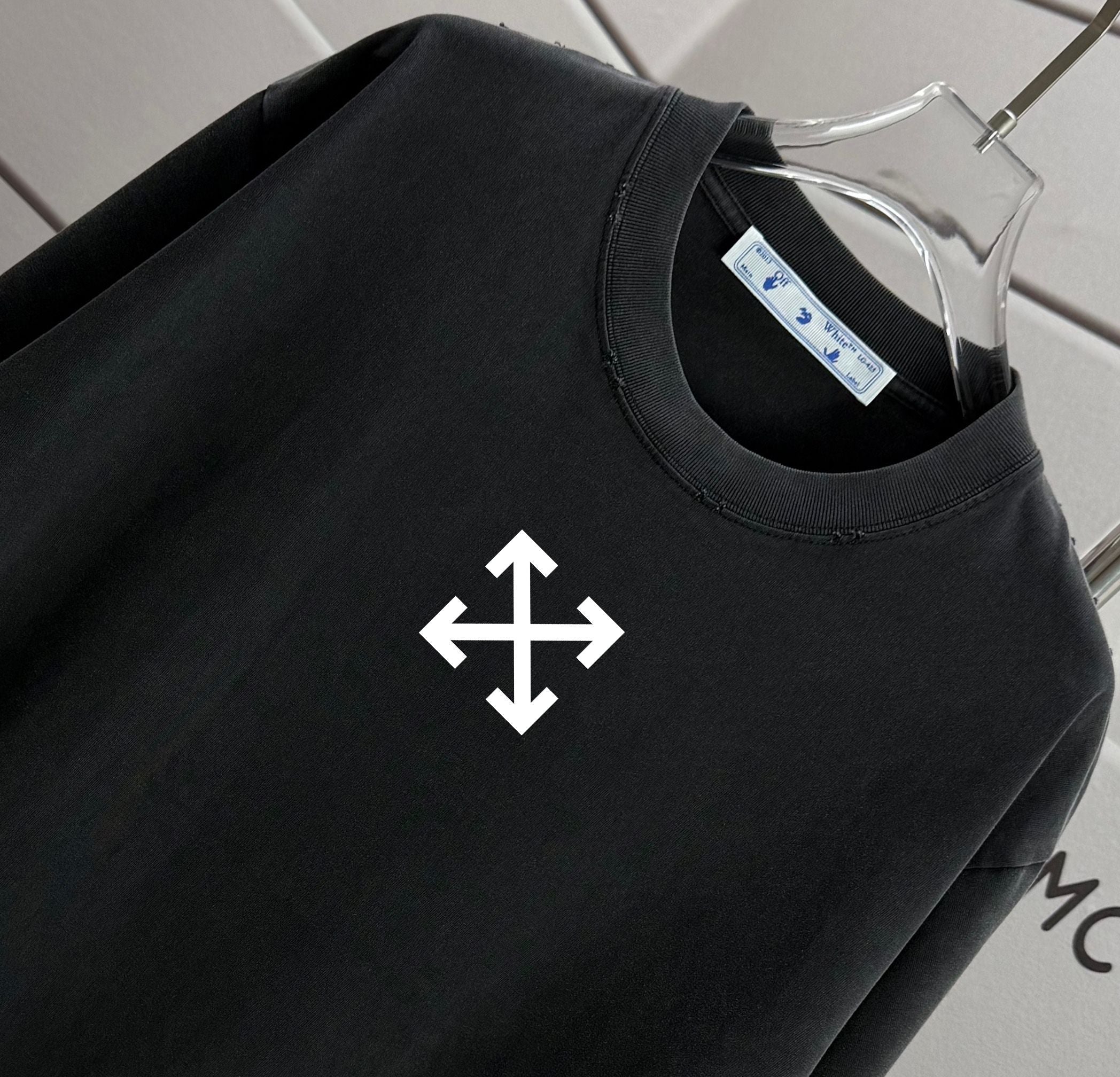 Black T-shirt neckline and chest white arrow-cross graphic, close-up