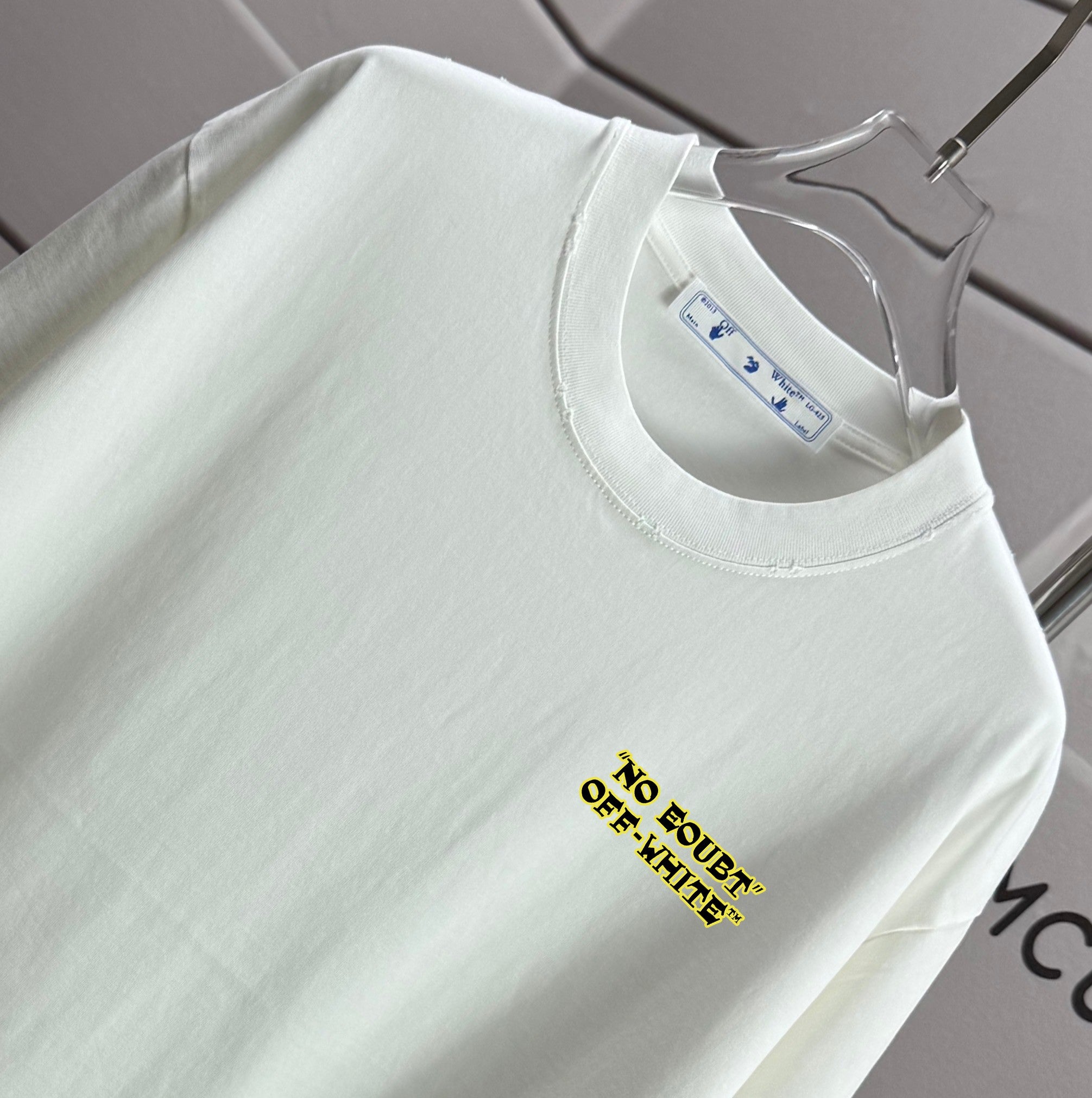 Off-white T-shirt close-up of round collar and small yellow chest text