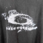 Close-up of dark T-shirt fabric with large white eye graphic and distressed text