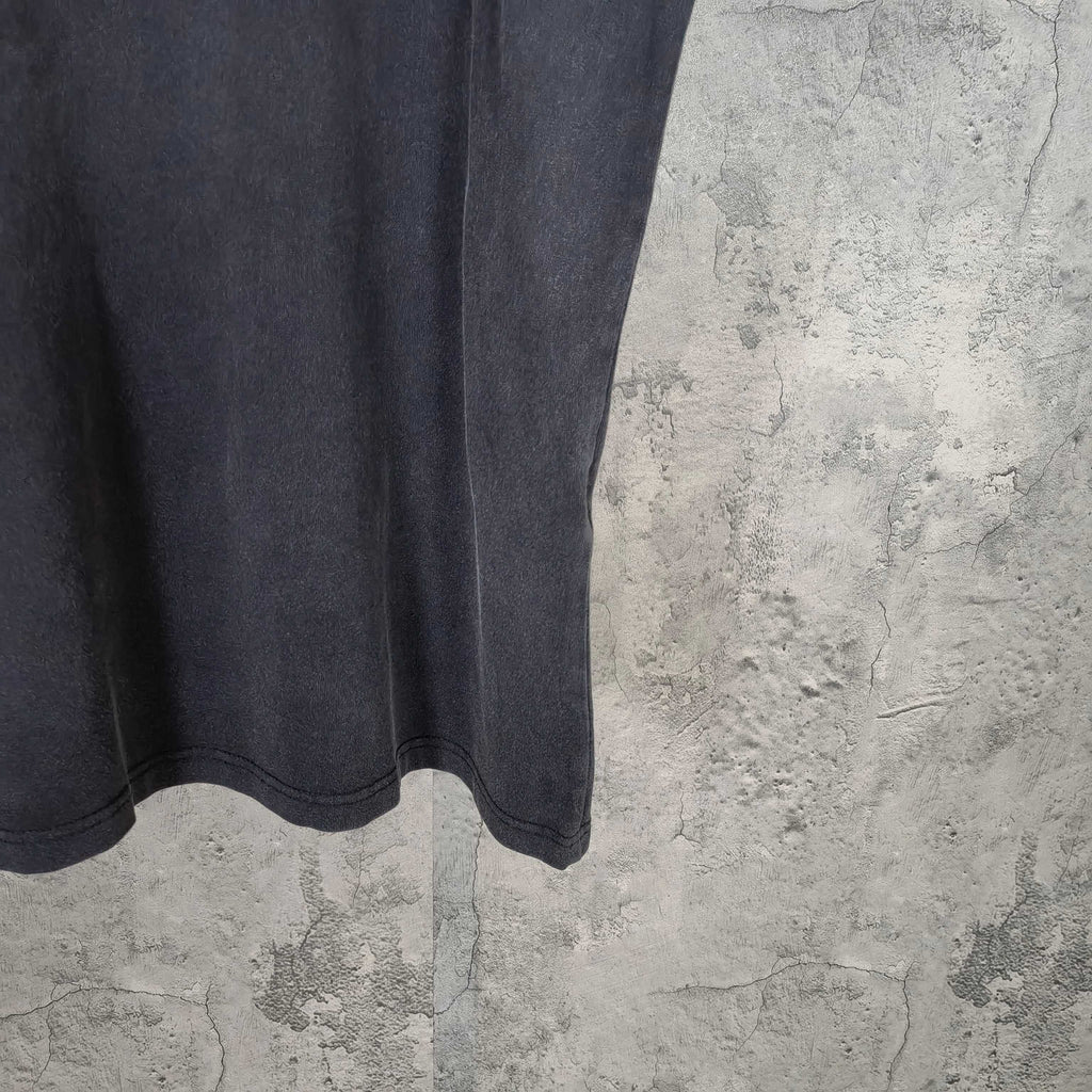 Dark wash T-shirt hem view with straight bottom edge and subtle wear marks