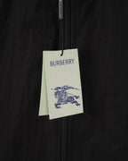 Burberry clothing tag hanging on dark jacket zipper area