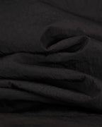 Black jacket interior lining fabric with soft wrinkled texture close-up