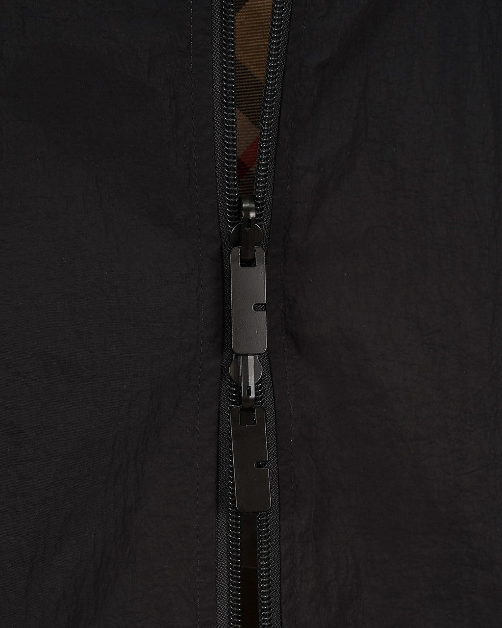 Burberry jacket zipper close-up with pull tab and dark fabric
