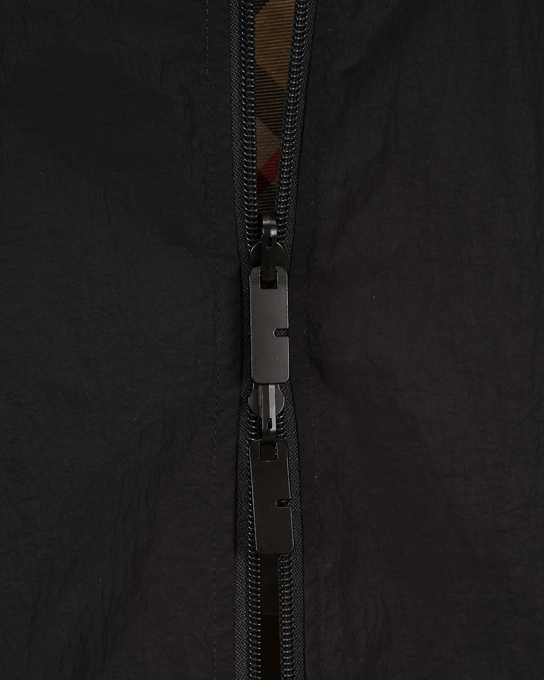 Burberry jacket zipper close-up with pull tab and dark fabric