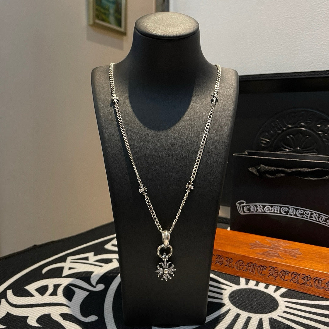 Silver-tone chain necklace on black bust with snowflake pendant and loop clasp