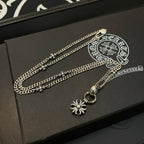 Silver-tone chain necklace with snowflake pendant and circular clasp on jewelry box