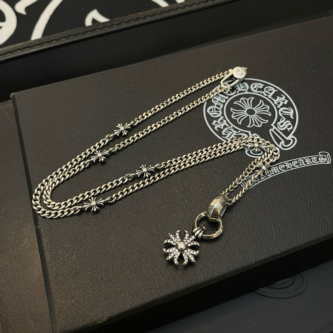 Silver-tone chain necklace with snowflake pendant and circular clasp on jewelry box