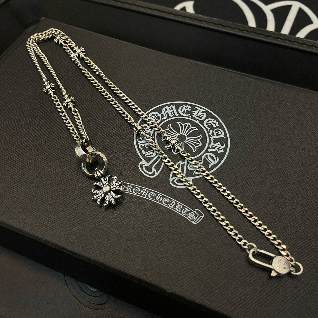 Silver-tone chain necklace with snowflake pendant and charm accents on jewelry box