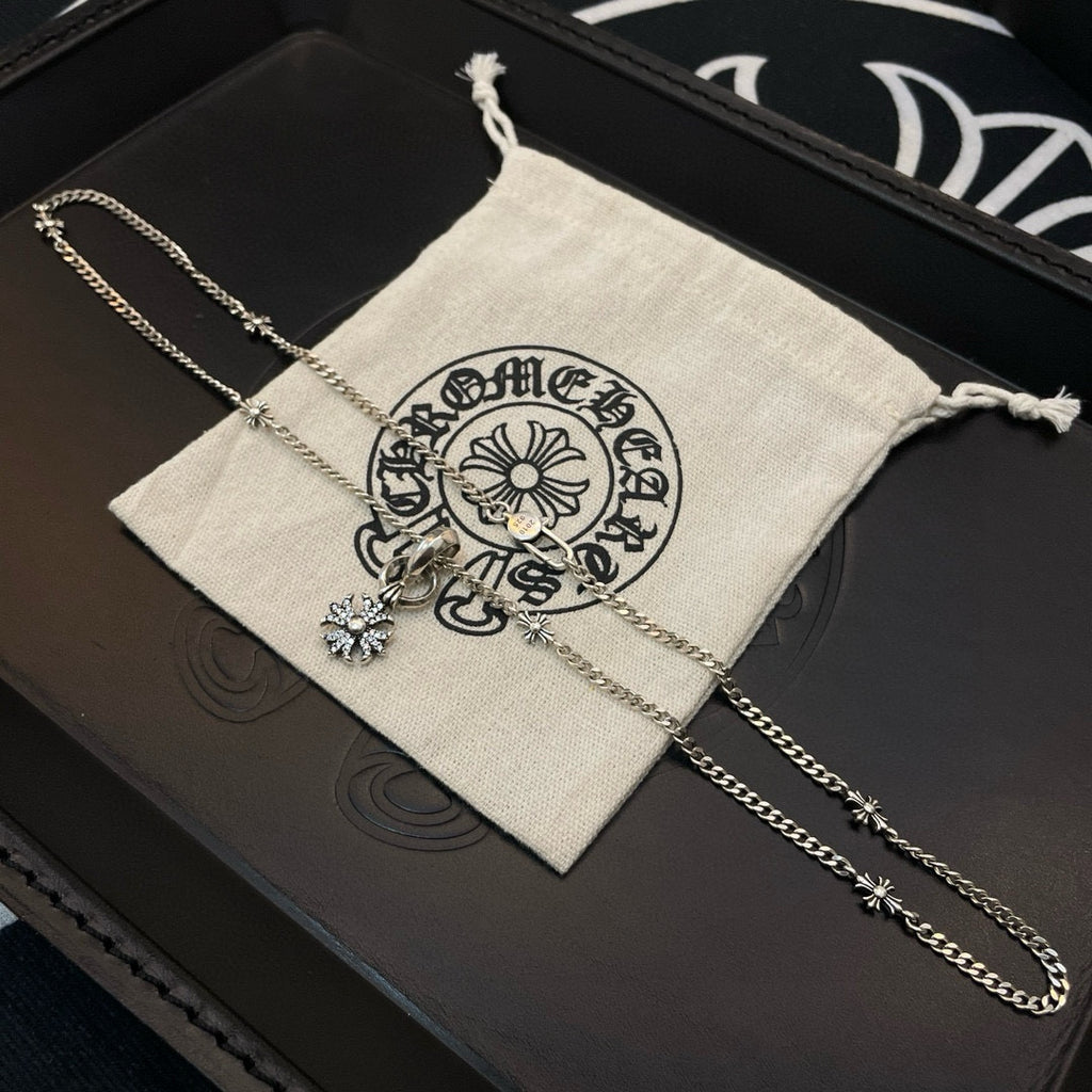 Silver-tone chain necklace with snowflake pendant on black jewelry box and cloth pouch