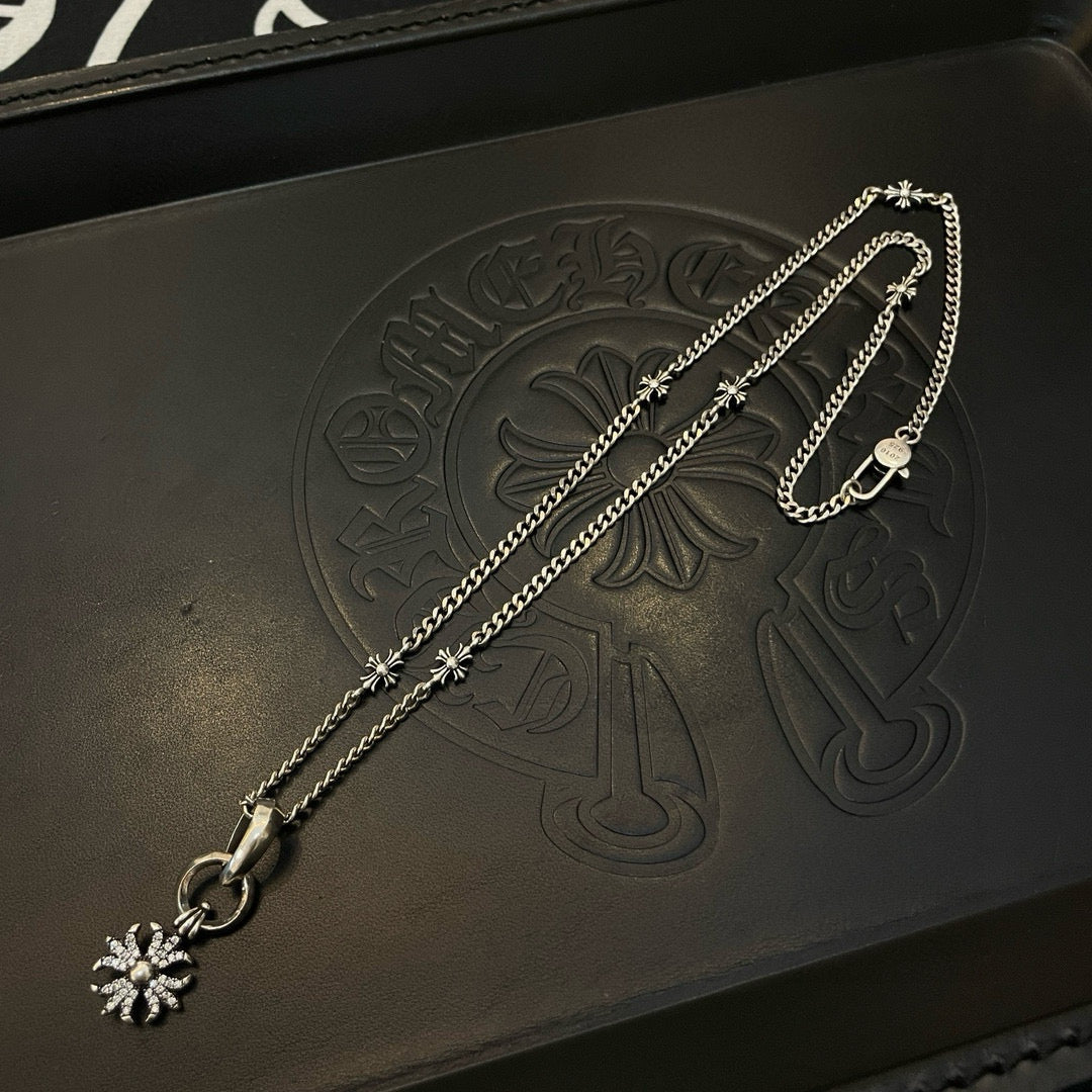 Silver-tone chain necklace with snowflake charm on dark leather pouch